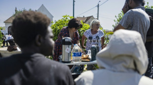 French volunteers hand migrants water beyond the crowded beach